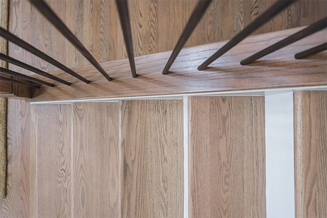 Closeup of where the banister spindles meet the stair tread to represent staircase remodel safety tips