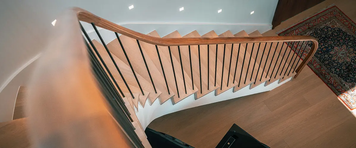 curved indoor stair railing with wood handrail and metal balusters