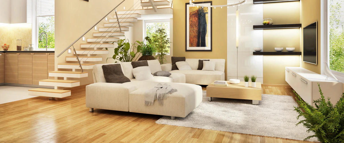 A sunlit, contemporary living room with a glossy light hardwood floor, a cream-colored sectional sofa, and modern open-riser stairs with cable railing.