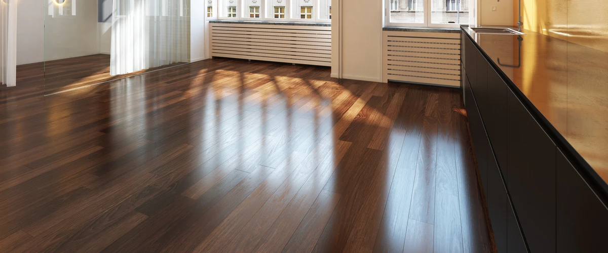 Polished dark hardwood floor reflecting sunlight in a modern interior featuring dark cabinetry and large window radiators.
