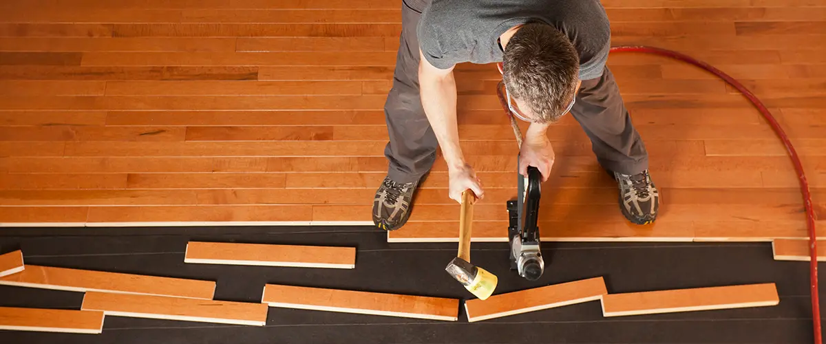 installing hardwood floor planks with nail gun and tools