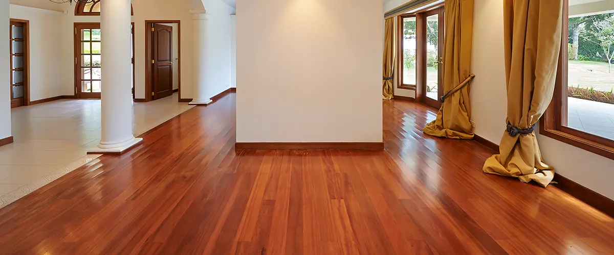 polished hardwood flooring in empty room with large windows