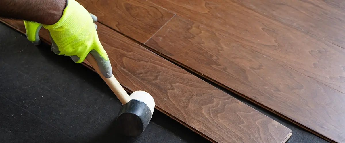 Hardwood Floor Installation in Bethesda, MD 2 installing hardwood planks with rubber mallet and spacing alignment