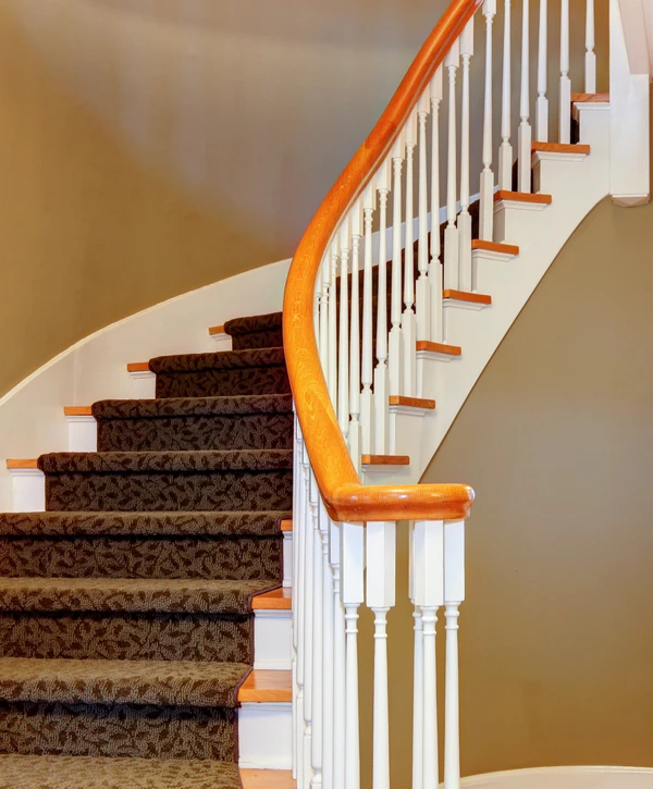 Curved wood handrail and white painted baluster stair railing installation on a carpeted staircase in Arlington, VA.