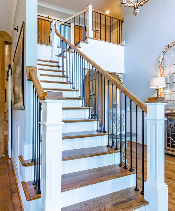 Traditional staircase featuring oak treads, white risers, and black iron spindles with a decorative wooden newel post in an Alexandria, VA home.