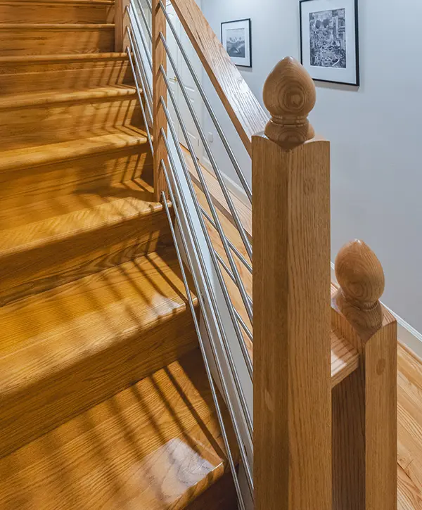 Close-up of hardwood staircase with stainless steel cable railing and custom wood newel posts