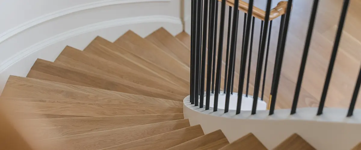 Stair Refinishing in Vienna, VA 2 Curved hardwood staircase with black iron balusters in luxury modern home interior