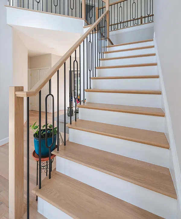 Stair Refinishing in Vienna, VA 1 Custom oak staircase with decorative iron balusters in bright two-story home foyer