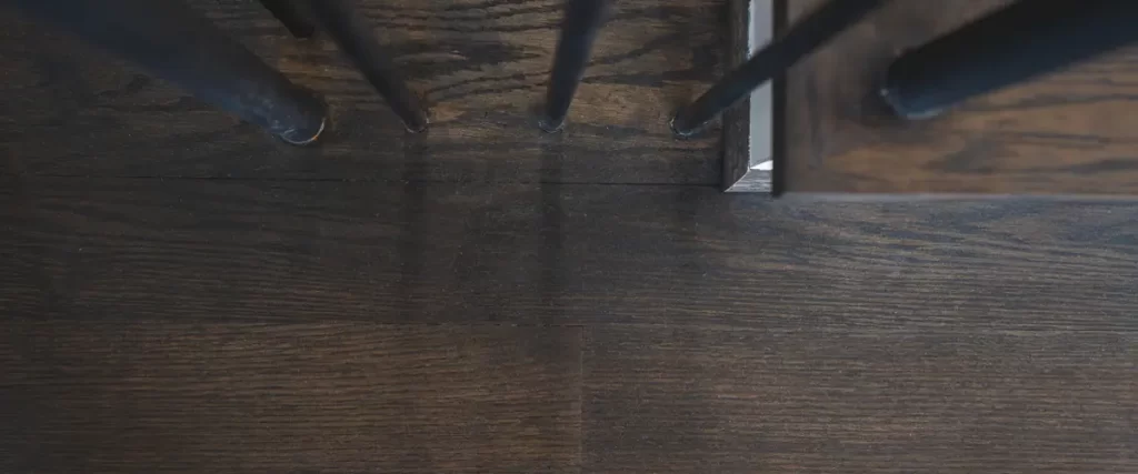 Solid vs Engineered Hardwood Flooring: The Honest Breakdown 1 Dark stained hardwood staircase with modern black metal balusters and custom wood flooring
