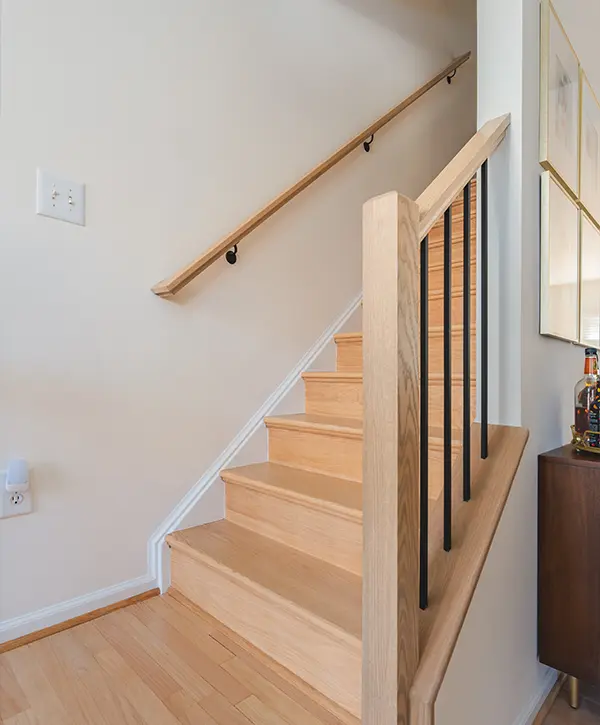 Light wood staircase with black iron balusters in modern residential home interior