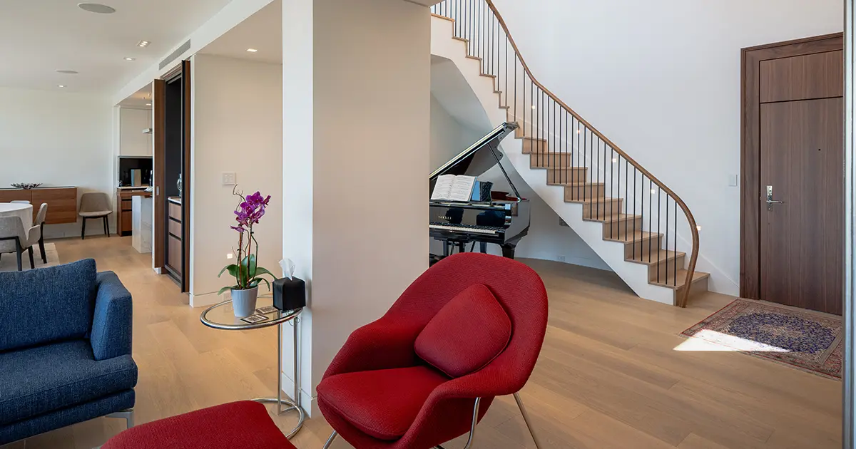 Modern luxury living room with curved wood staircase and contemporary hardwood flooring