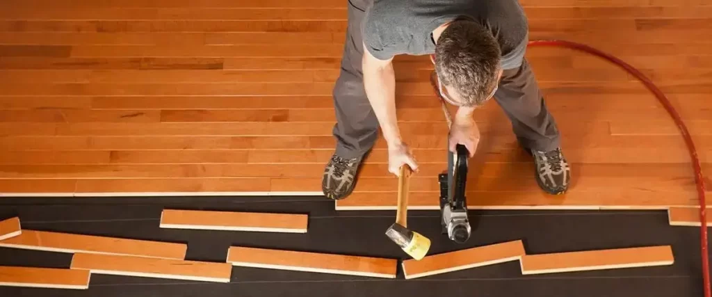 How to Acclimate Hardwood Flooring (Without Wrecking Your Floor) 1 Professional hardwood floor installation with nail gun and wood planks in residential home